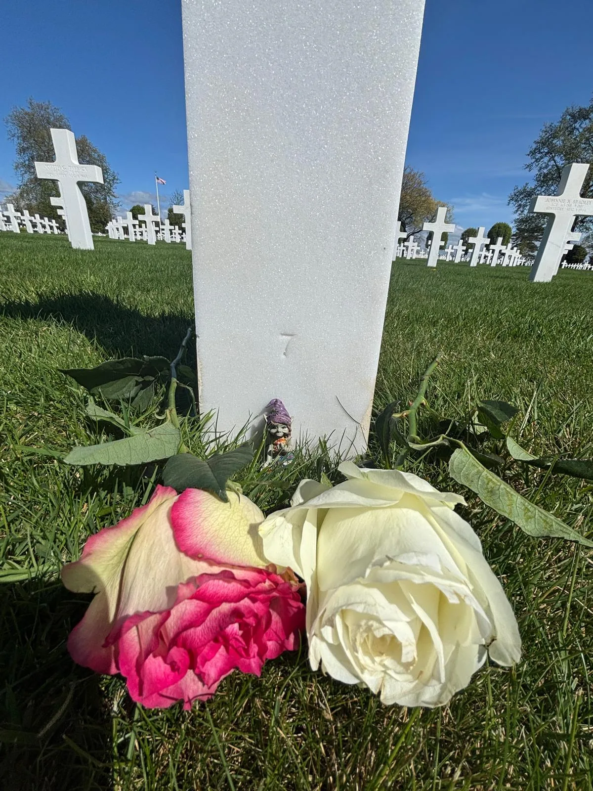 Abel's cross with a red rose and a small soldier figurine placed on top
