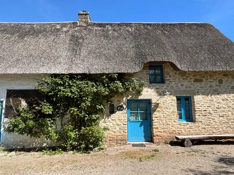 Thatched cottage with blue shutters and white stone walls at Kerhinet
