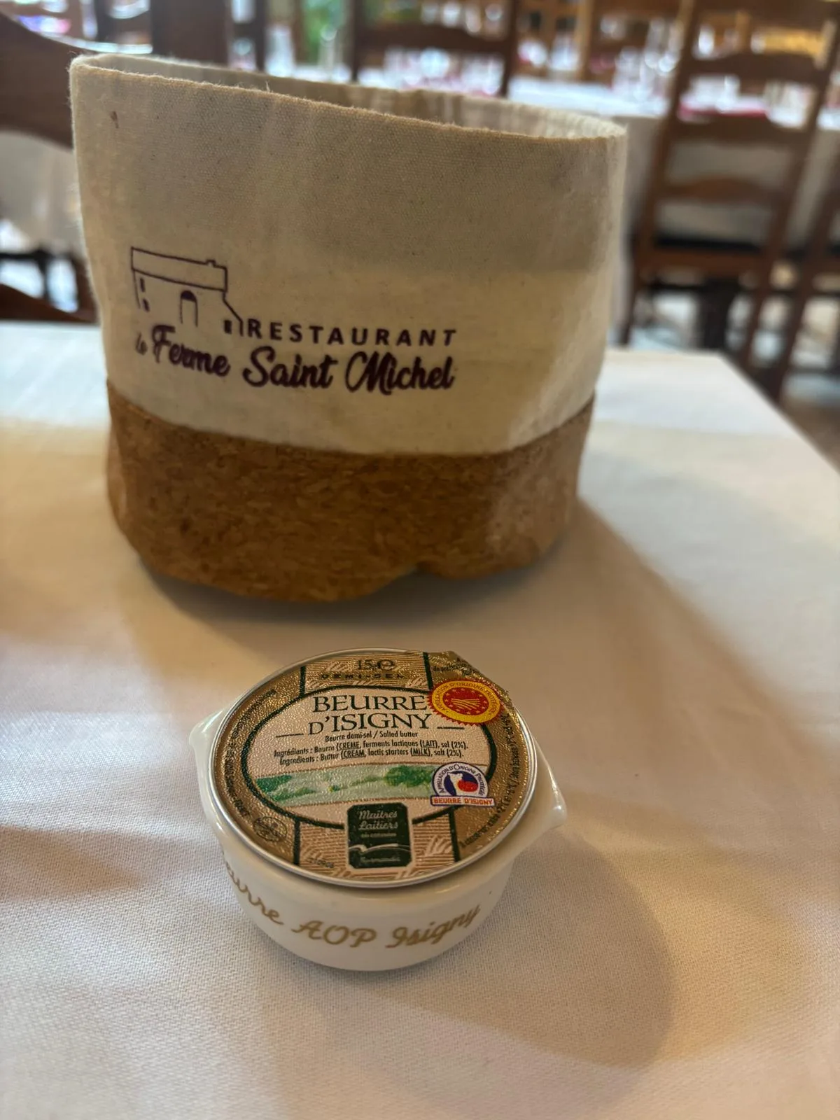 A pot of Beurre d'Isigny AOP butter beside the restaurant's branded bread basket