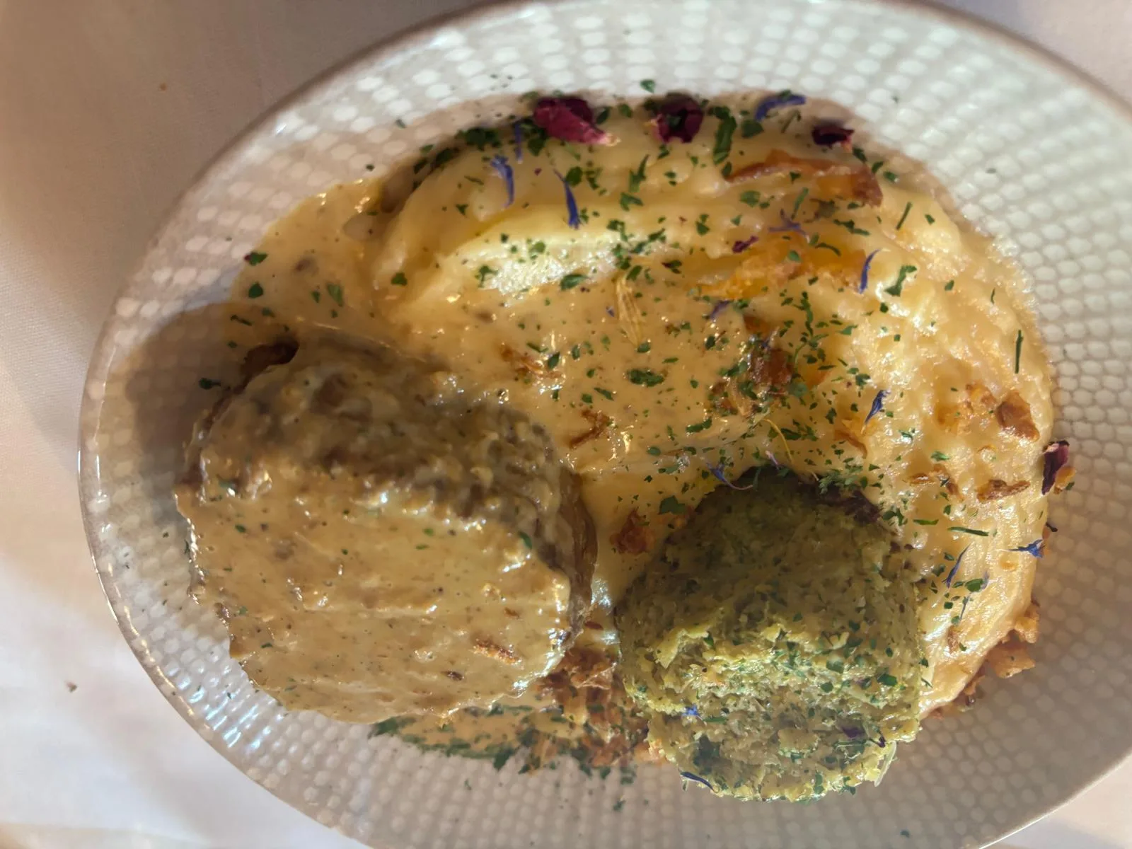 A salt-meadow lamb parmentier with herbed quenelle, green sauce and gratin topping on a textured plate