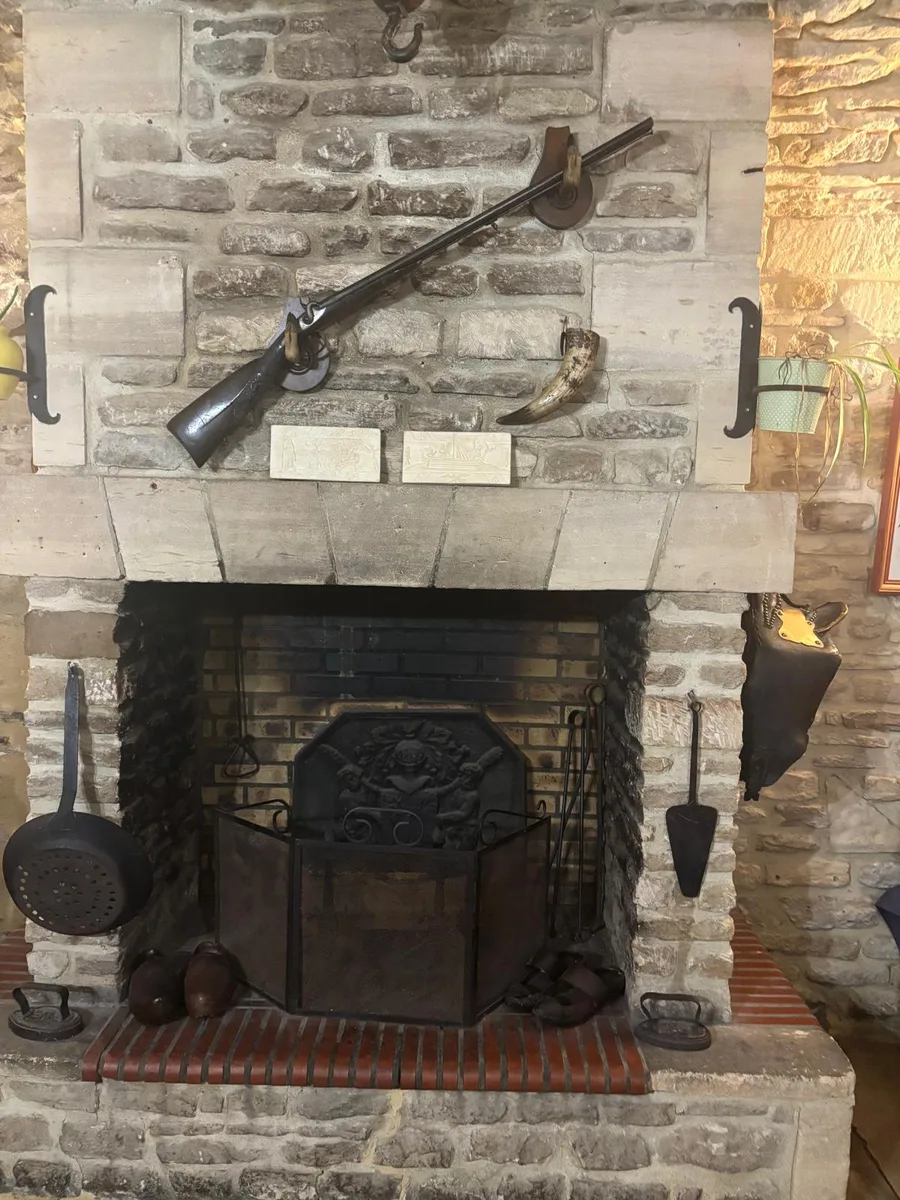 An antique rifle and cast-iron fireback above the fireplace hearth