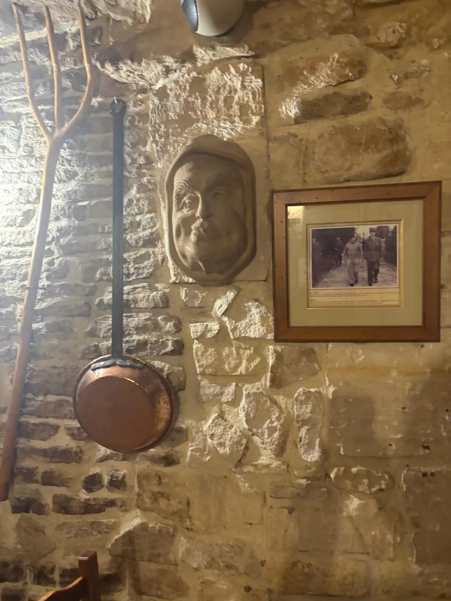 A copper pan and a framed black and white photograph of soldiers on the stone wall