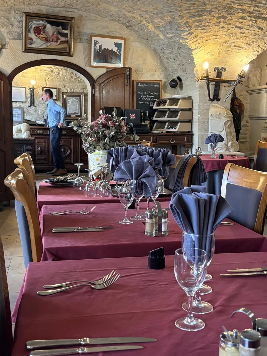 The dining room with tables dressed in red linen and a member of the family at work