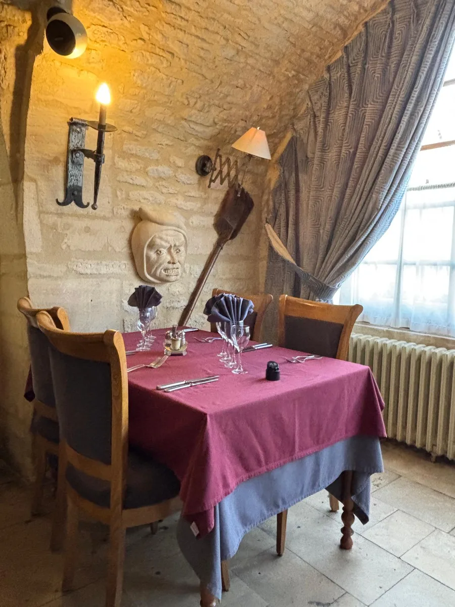 A table set beneath a grotesque carved stone face and a wrought-iron candle sconce