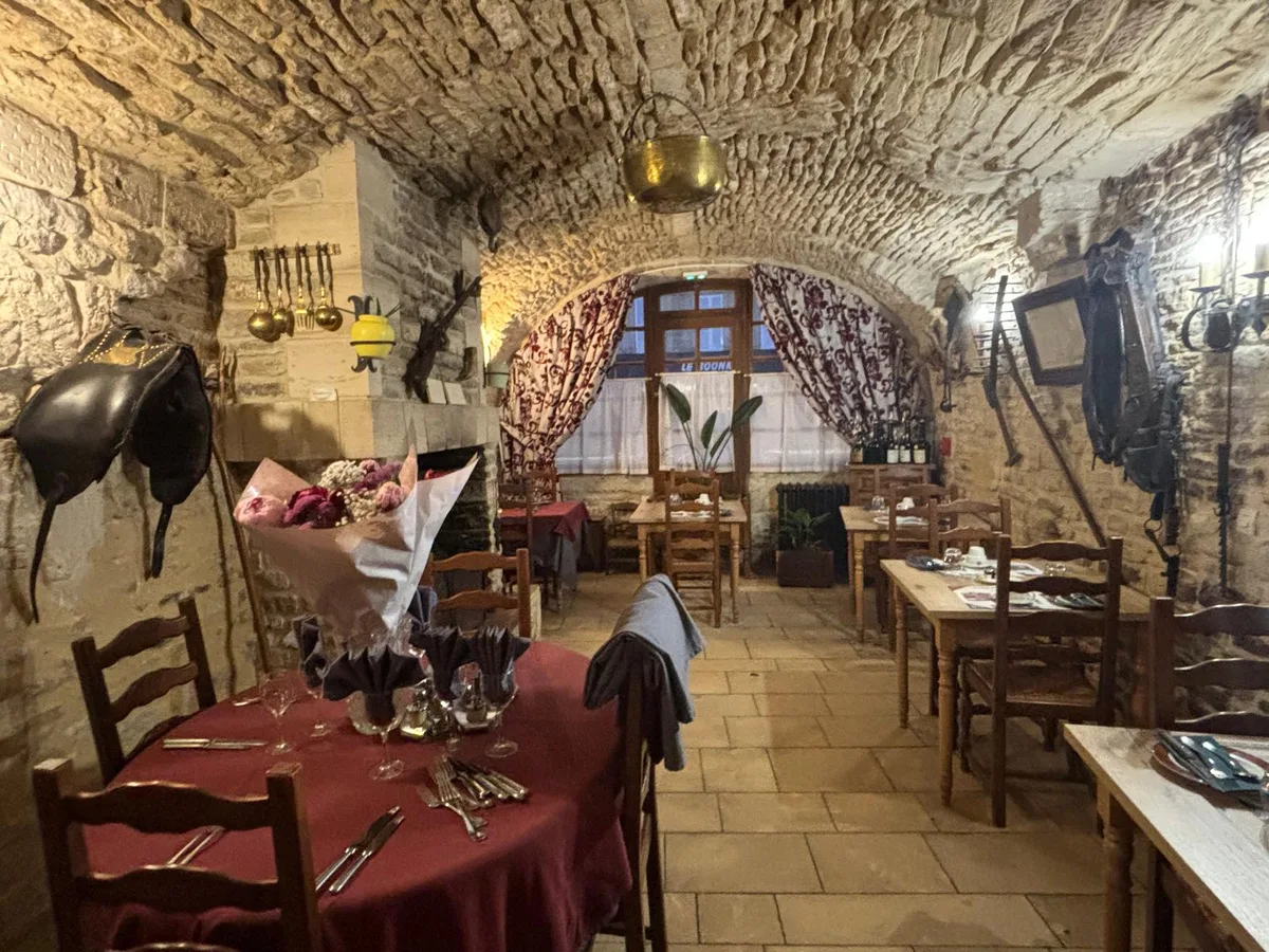 A rustic vaulted dining room with copper cauldron, fireplace and curtained window