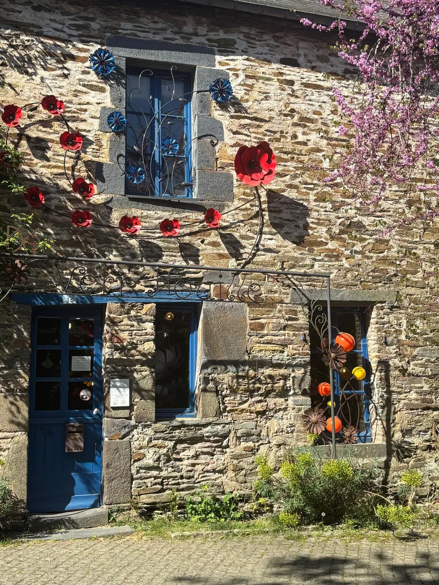 Stone house decorated with handcrafted metal poppies and a cherry blossom tree
