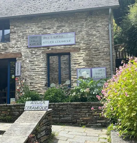 A Breton ceramic artisan's workshop in a stone building at La Gacilly, with an open door and flowers along the wall